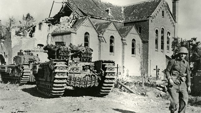 Zwart-wit foto met een legertank en militair voor een halfverwoeste kerk